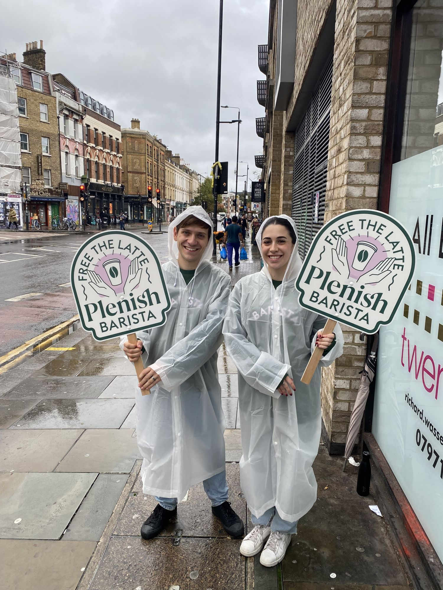@ staff in clear raincoats holding signs that read Plenish at Hel's pop-up