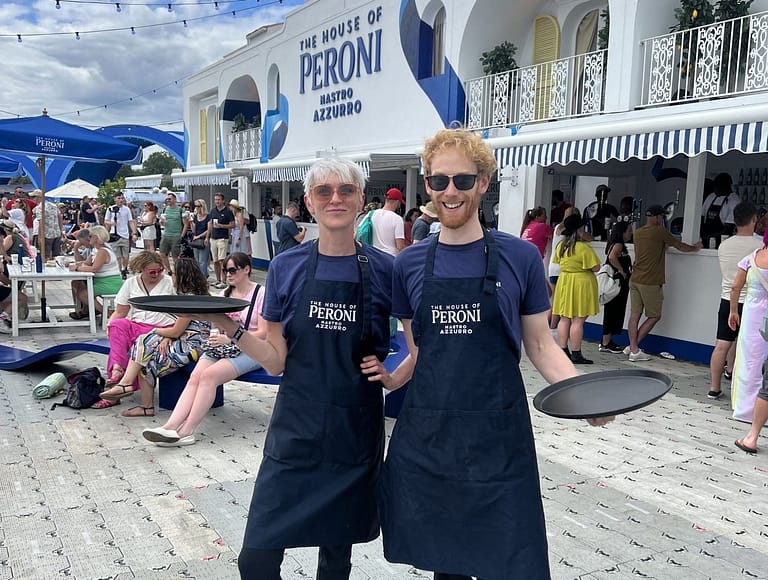 Male and female in blue tee shirts and aprons working at a festival