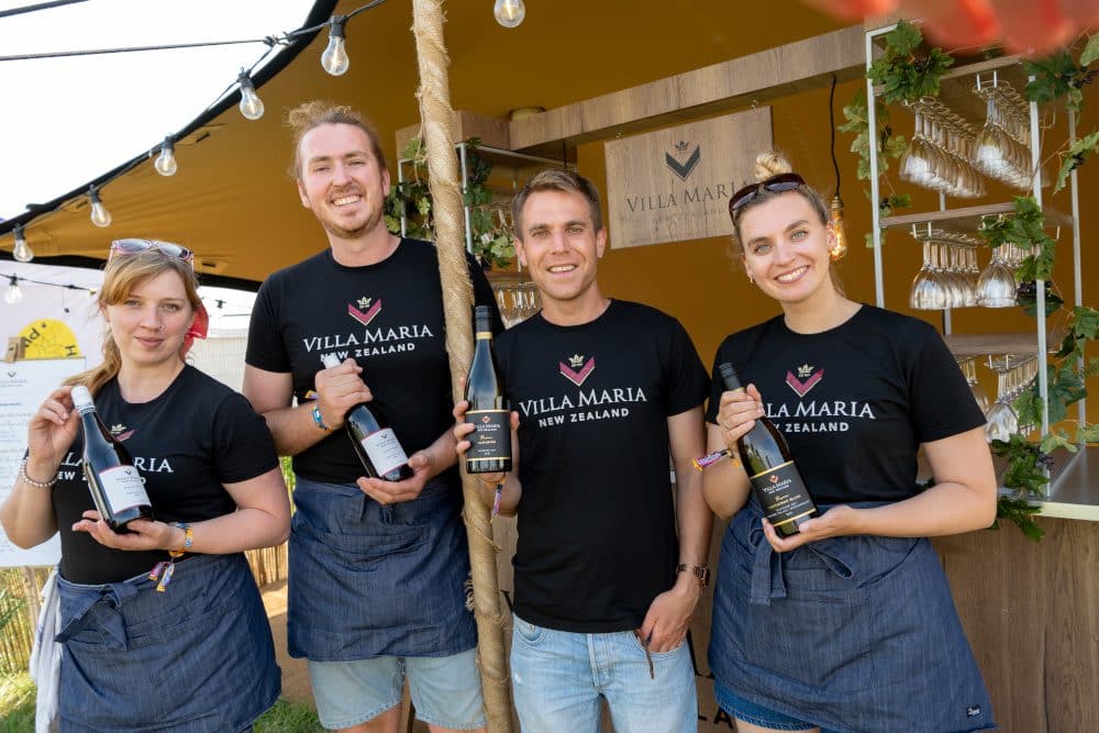 Four youth dressed in Villa Maria branded tee shirts holding bottles of wine at a festival