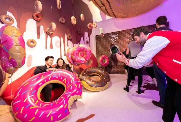 consumers sitting amongst blow up doughnuts have photos taken - technology in the events industry.